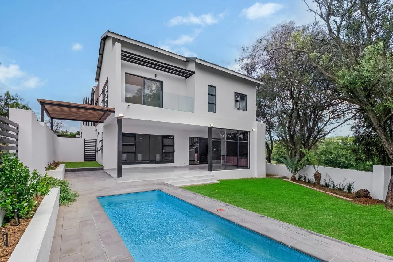 Helderfontein modern two-storey home with swimming pool, manicured lawn, patio and surrounding trees.