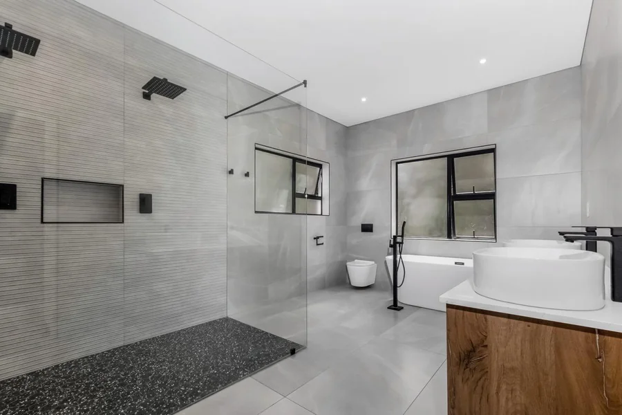Helderfontein bathroom with walk-in shower, freestanding bathtub, vanity and black-framed windows.