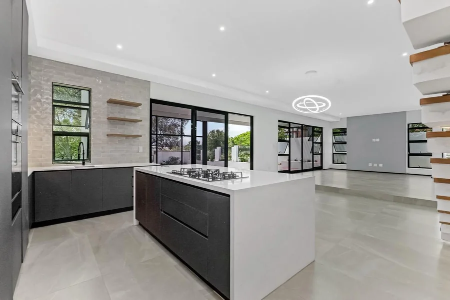 Helderfontein open-plan kitchen and living area with a large island, black cabinetry, glass doors and built-in shelving.