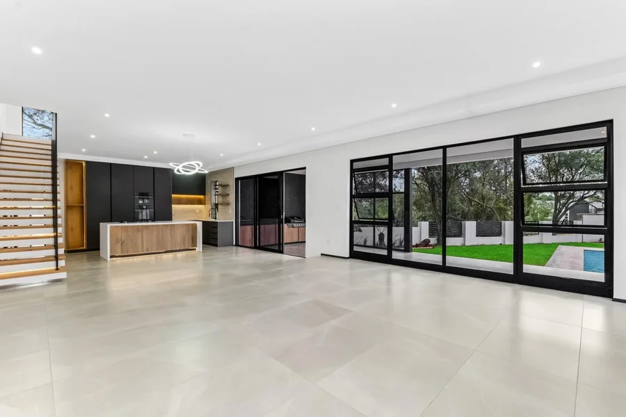 Helderfontein open-plan living area with kitchen, expansive glazing and a garden and pool outlook.