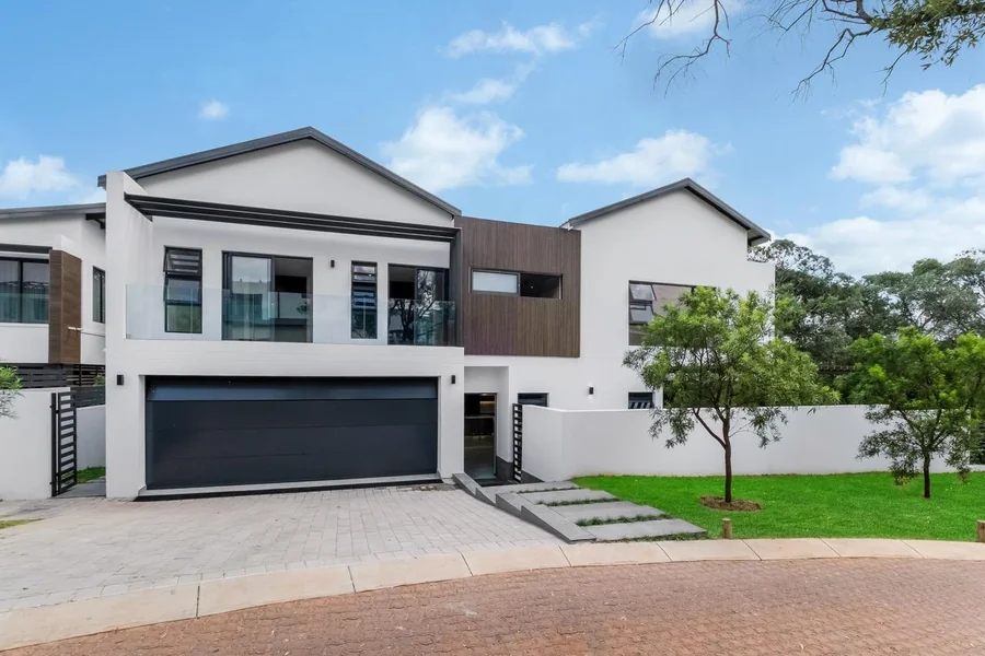 Helderfontein two-storey home exterior with garage, balcony, driveway, lawn and trees.