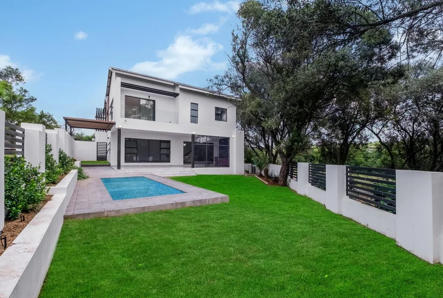 Helderfontein two-storey home with pool, lawn, boundary walls and mature trees.